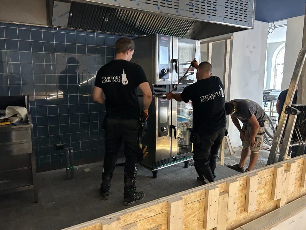 Två tekniker från Storkökskliniken installerar staplade kombiugnar i ett kök under ombyggnad