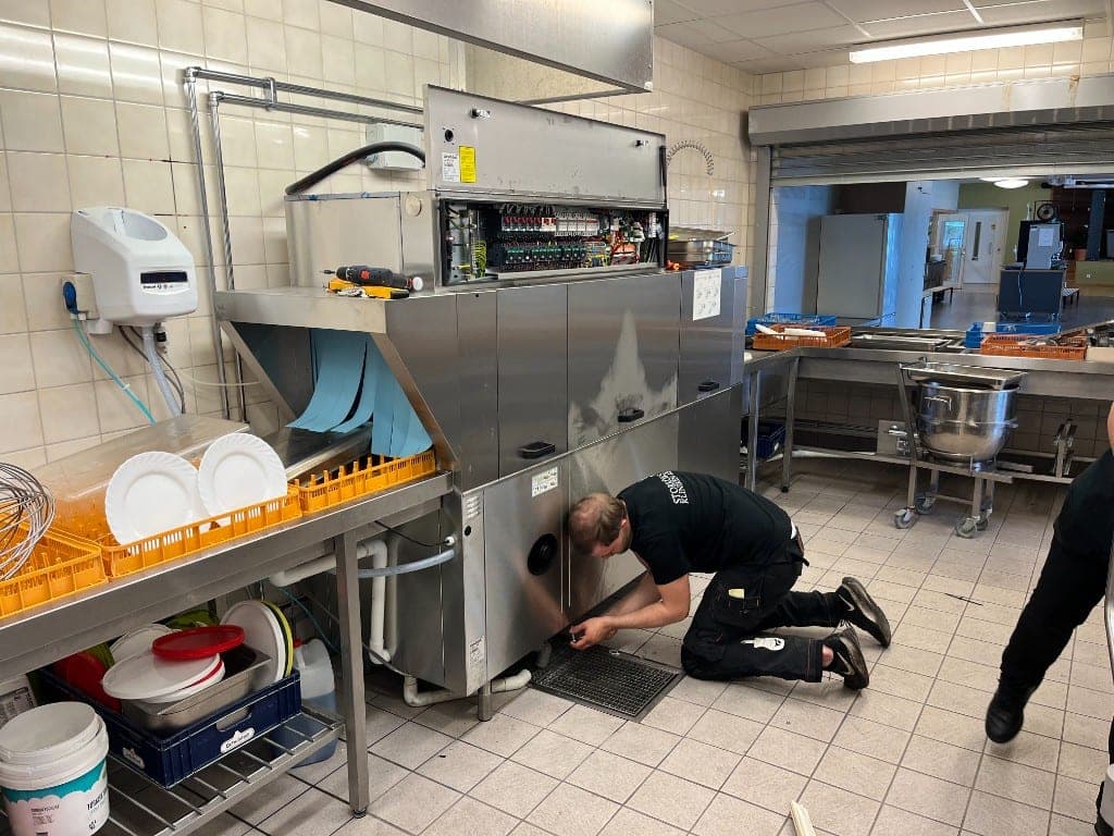 Tekniker installerar en tunneldiskmaskin i ett storkök