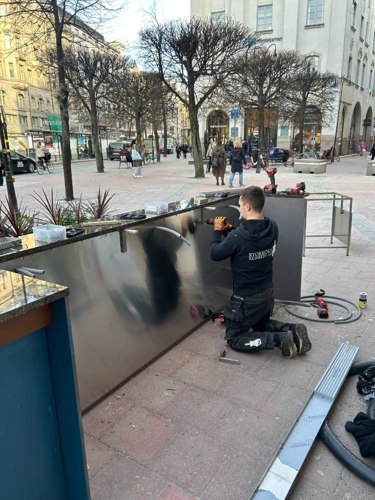 Tekniker från Storkökskliniken monterar rostfri panel på en utebar i Stockholms innerstad